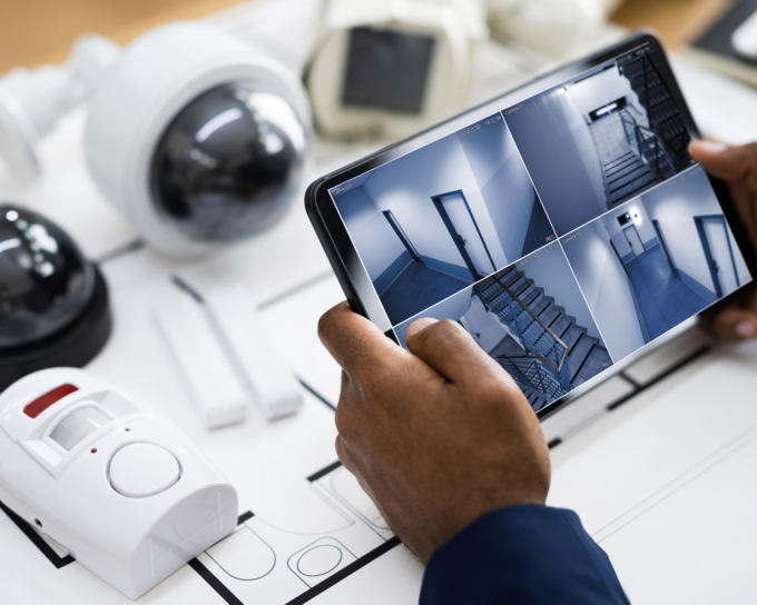 tablet showing security footage with security cameras in background