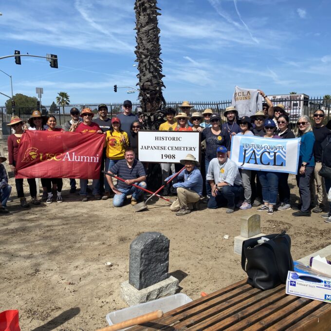 large group of people holding USC and Ventura County JACL banners at Historic Japanese Cemetery