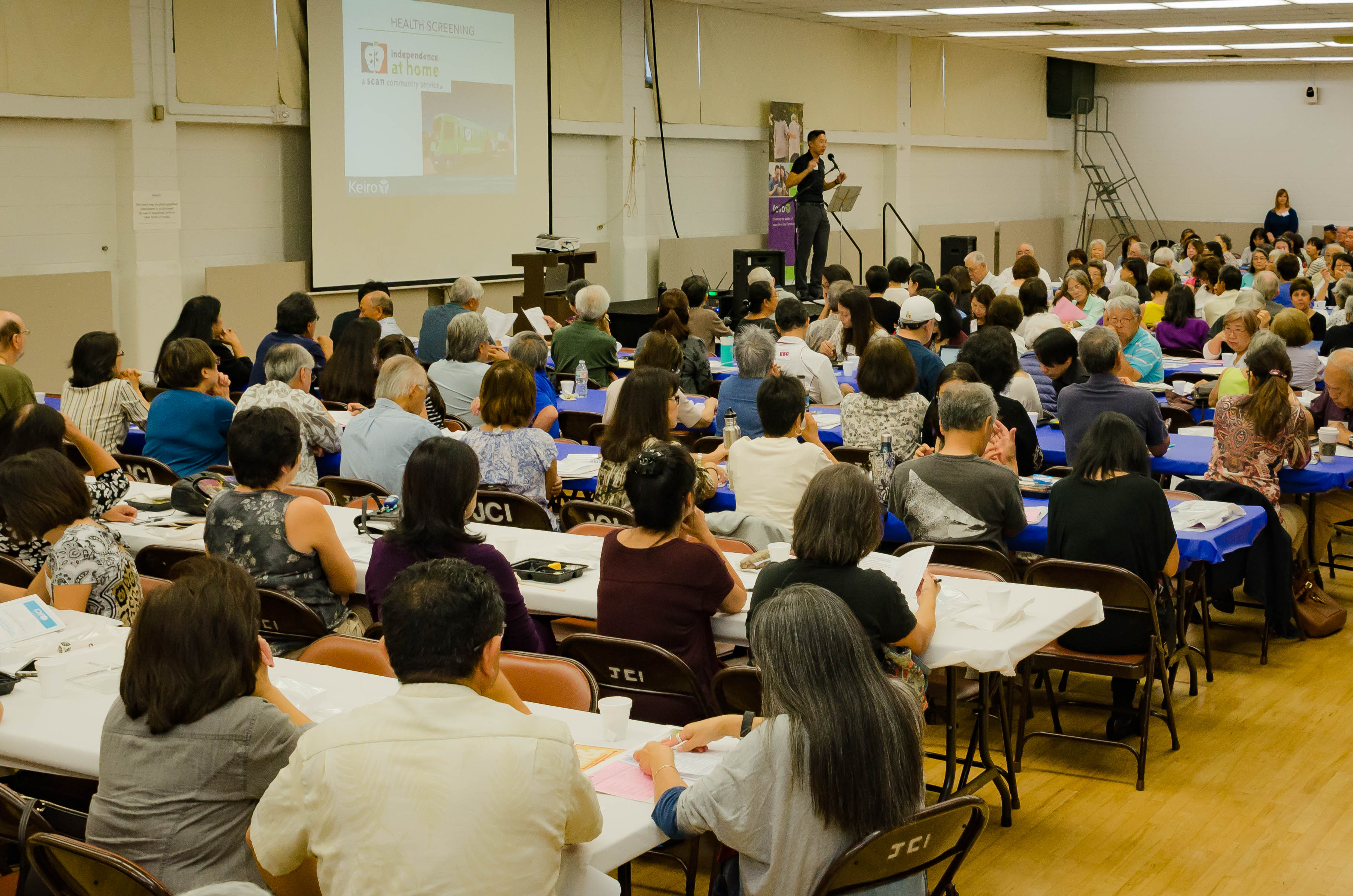 Caregiver conference audience members watch Brandon Leong speak