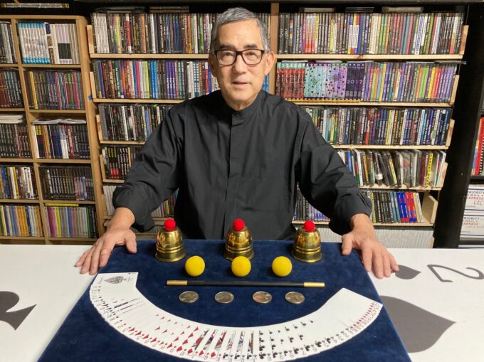 magician with cards laid out on table and other magic props