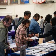 conference attendees getting papers from resource fair table