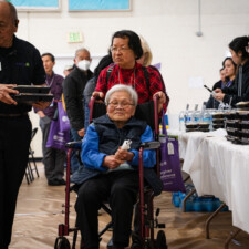 conference attendee pushing wheelchair with another attendee while picking up bento