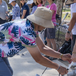 a man in a Hawaiian shirt adjusting a woman's golf swing
