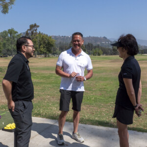 a man in black, woman in black, and a man in white laughing