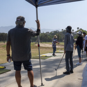 a man in gray watching the golf lesson