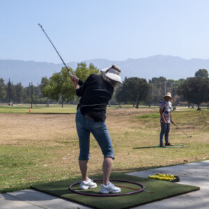 a woman in black swinging a golf ball