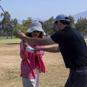 a man in black demonstrating to a woman in pink on how to swing
