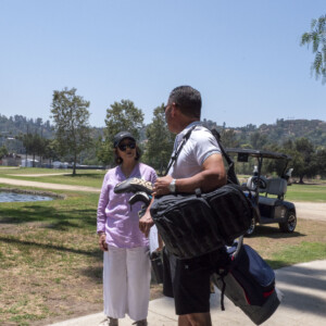 man with golf clubs talking with women in a lilac shirt