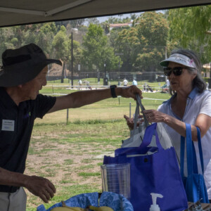 a man in black handing a woman in white a bag