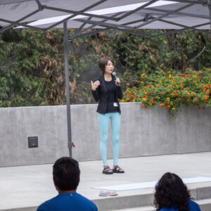 a woman in black talking to a group of people