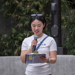 a woman in beige talking into a microphone