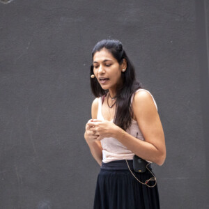a woman in beige talking with a group of people