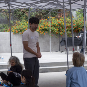 a man in a biege shirt talking with a woman in blue
