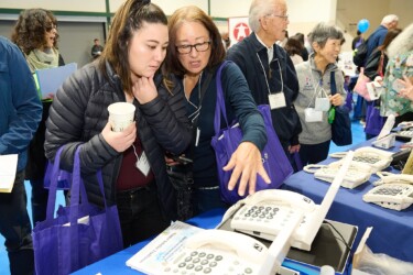 Two attendees looking at assistive telephone