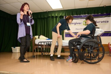 presenter speaking while two people demonstrate wheel chair