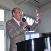 Tom Iino talking into mic doing a toast