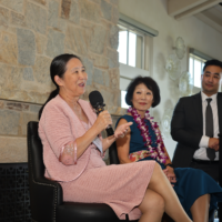Lynn Miyamoto talking into mic with Beverly Ito and Kevin Onishi on stage