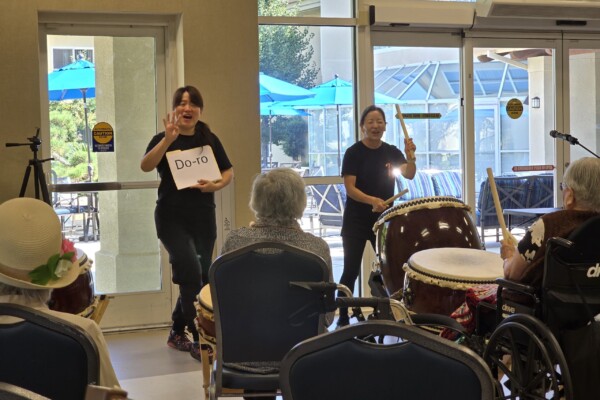 two people demonstrating taiko to people in wheelchairs