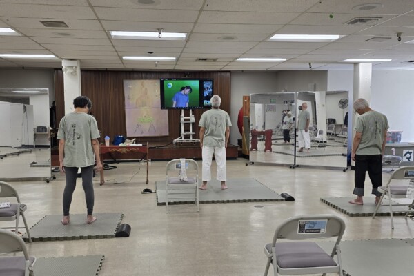 three people standing on mats doing exercises