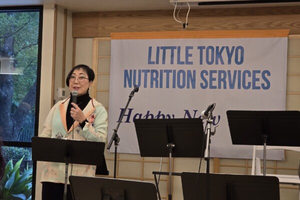 woman speaking into mic in front on sign that says "Little Tokyo Nutrition Services"