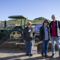 three people posing in front of a tractor