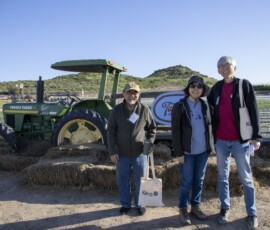 three people posing in front of a tractor