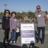 two women and one man standing next to a sign