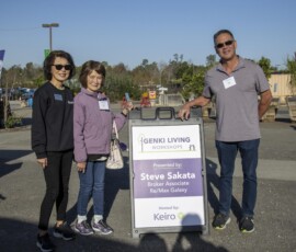 two women and one man standing next to a sign