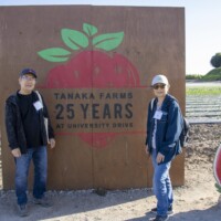 two people standing in front of Tanaka sign