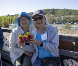 two woman holding a box of strawberries