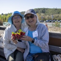 two woman holding a box of strawberries