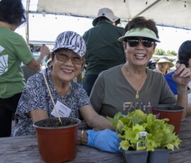 two woman smiling and holding plants
