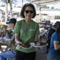 woman in green shirt with plates of food