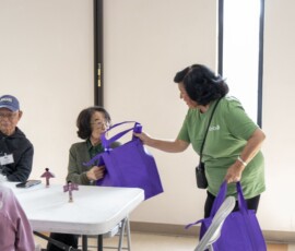 a woman in green handing a purple bag