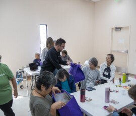 man in black handing a purple bag to a woman