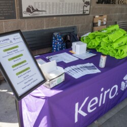purple table with green bags and a sign