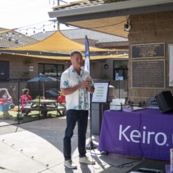 a man in white shirt talking with a mic