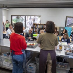 a woman in brown and a woman in red talking to a group of people
