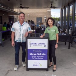 a man in white and a woman in green posing with a sign