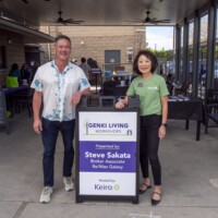 a man in white and a woman in green posing with a sign