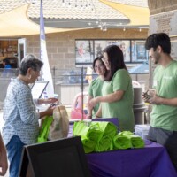 a group of people in green smiling with a woman in gray