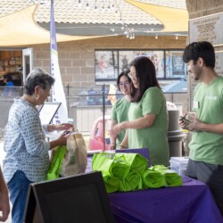 a group of people in green smiling with a woman in gray