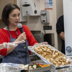 a woman in red holding a tray of tofu
