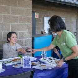 a woman in green handing a woman in gray mochi