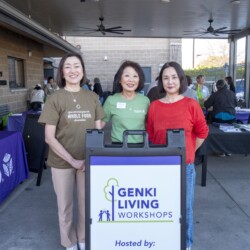 a woman in brown, a woman in green, and a woman in red posing by a sign