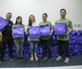 group of people in green shirts holding purple bags