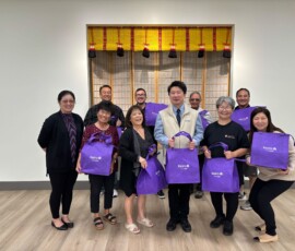 a group of people smiling and holding a purple bag