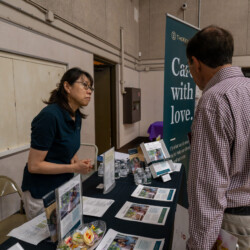 a woman in a green polo listening to a man in plaid talk