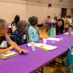a group of people talking by a purple table