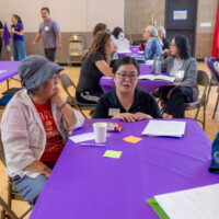 Heather Harada talking with people at a purple table